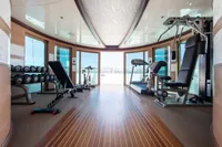 Luxurious yacht gym with modern equipment, featuring panoramic windows and sleek wooden flooring.