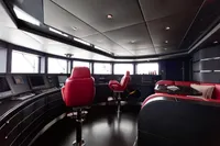 Luxurious yacht interior with red seating, modern control panels, and panoramic windows, Oceanco Custom 2001.