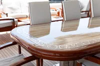 Luxurious yacht deck with elegant wooden table and cushioned chairs, Oceanco Custom 2001.