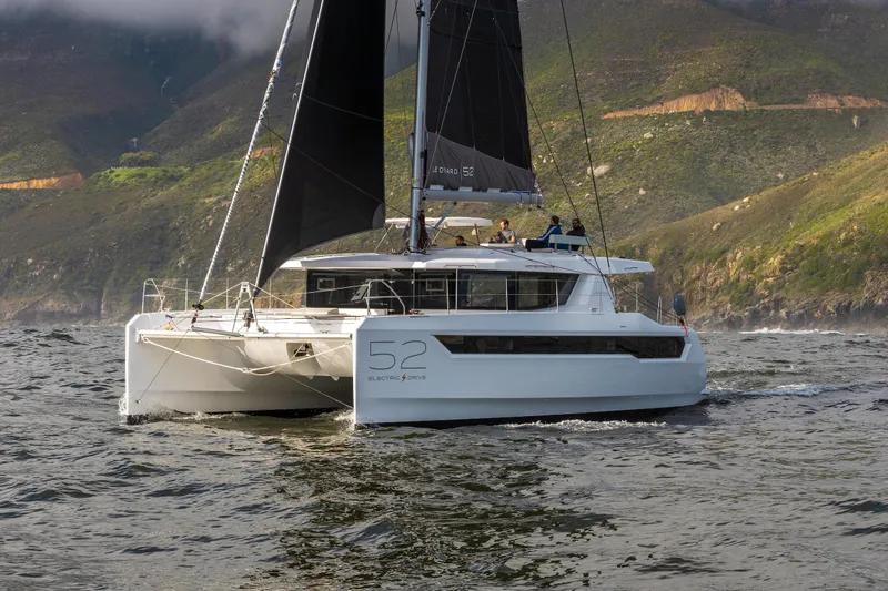 Faste Yacht Photos Pics 2025 Leopard 52 catamaran sailing near scenic coastline, featuring sleek design and electric drive.