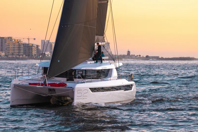 Faste Yacht Photos Pics 2025 Leopard 52 catamaran sailing at sunset near urban coastline.