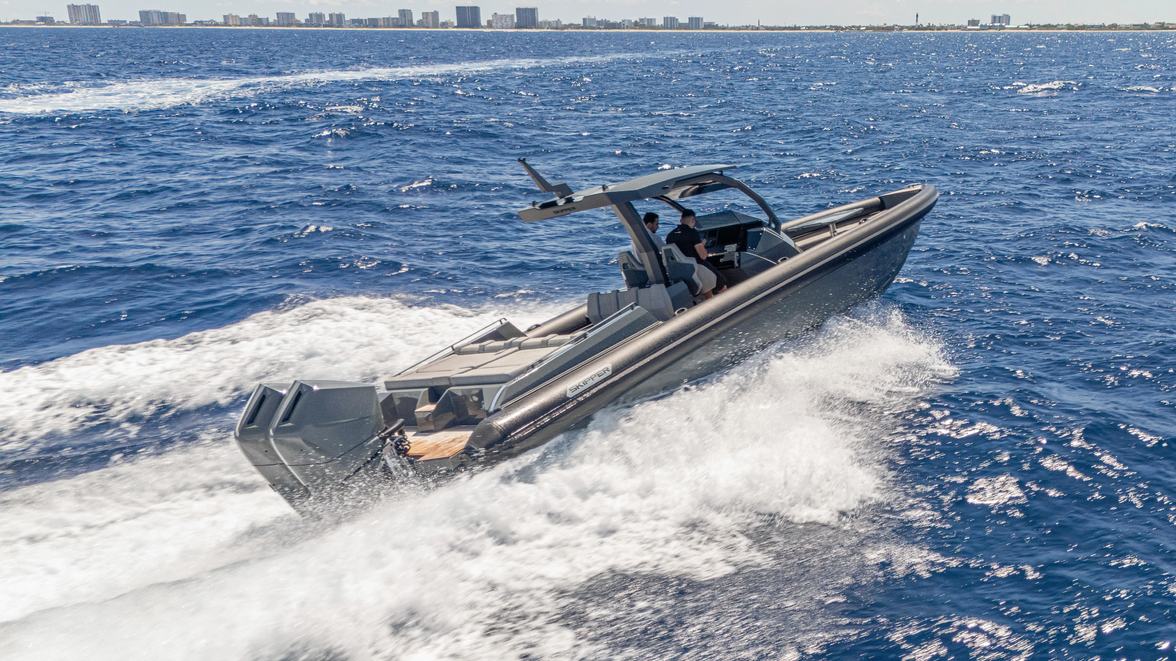 Skipper 38 Twin Mercury 400 Verado - Sunbed Ed. Yacht Photos Pics 2025 Skipper-BSK 38 boat cruising on open sea with city skyline in background.