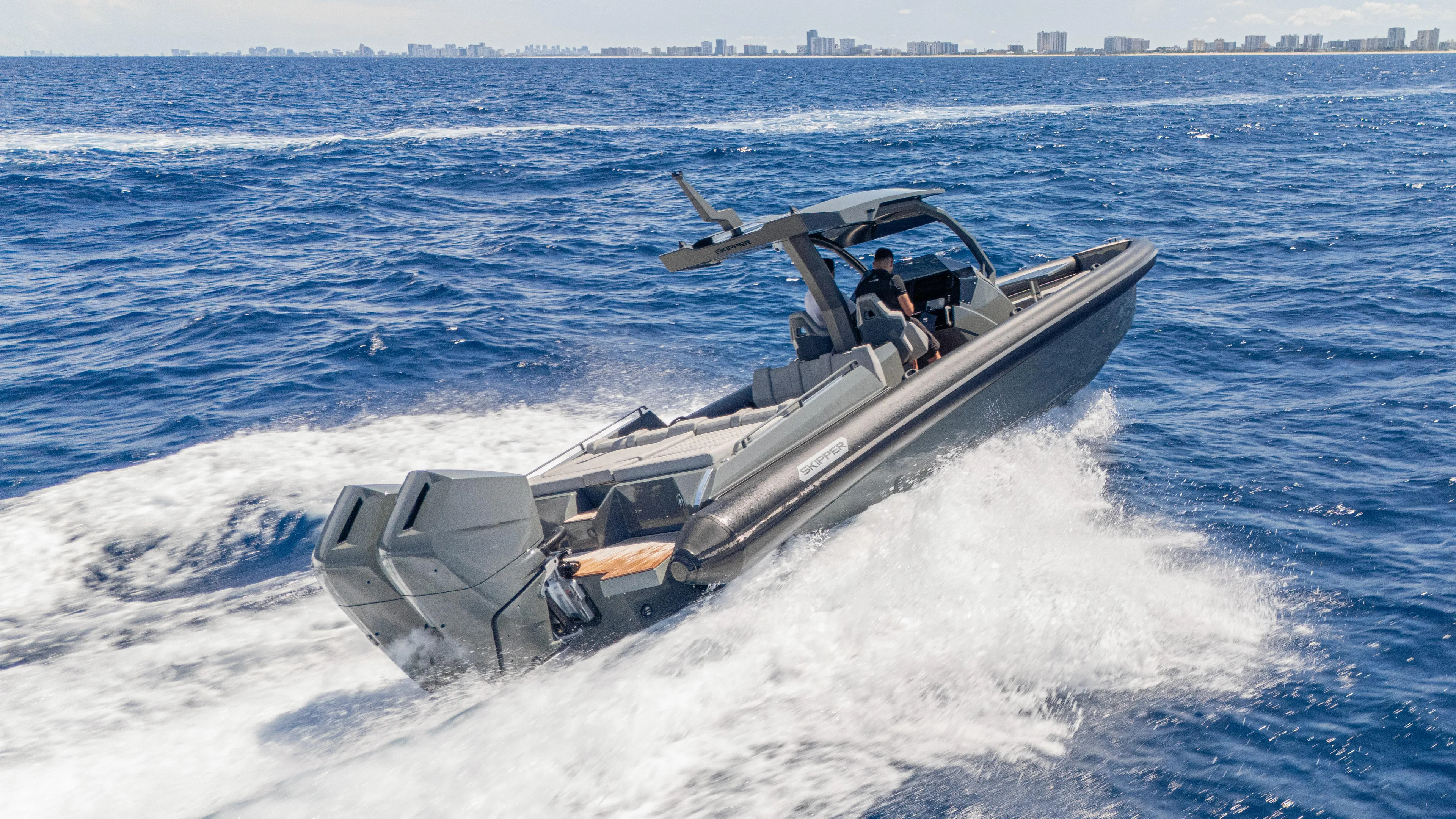 Skipper 38 Twin Mercury 400 Verado - Sunbed Ed. Yacht Photos Pics 2025 Skipper-BSK 38 boat cruising on open sea with city skyline in background.