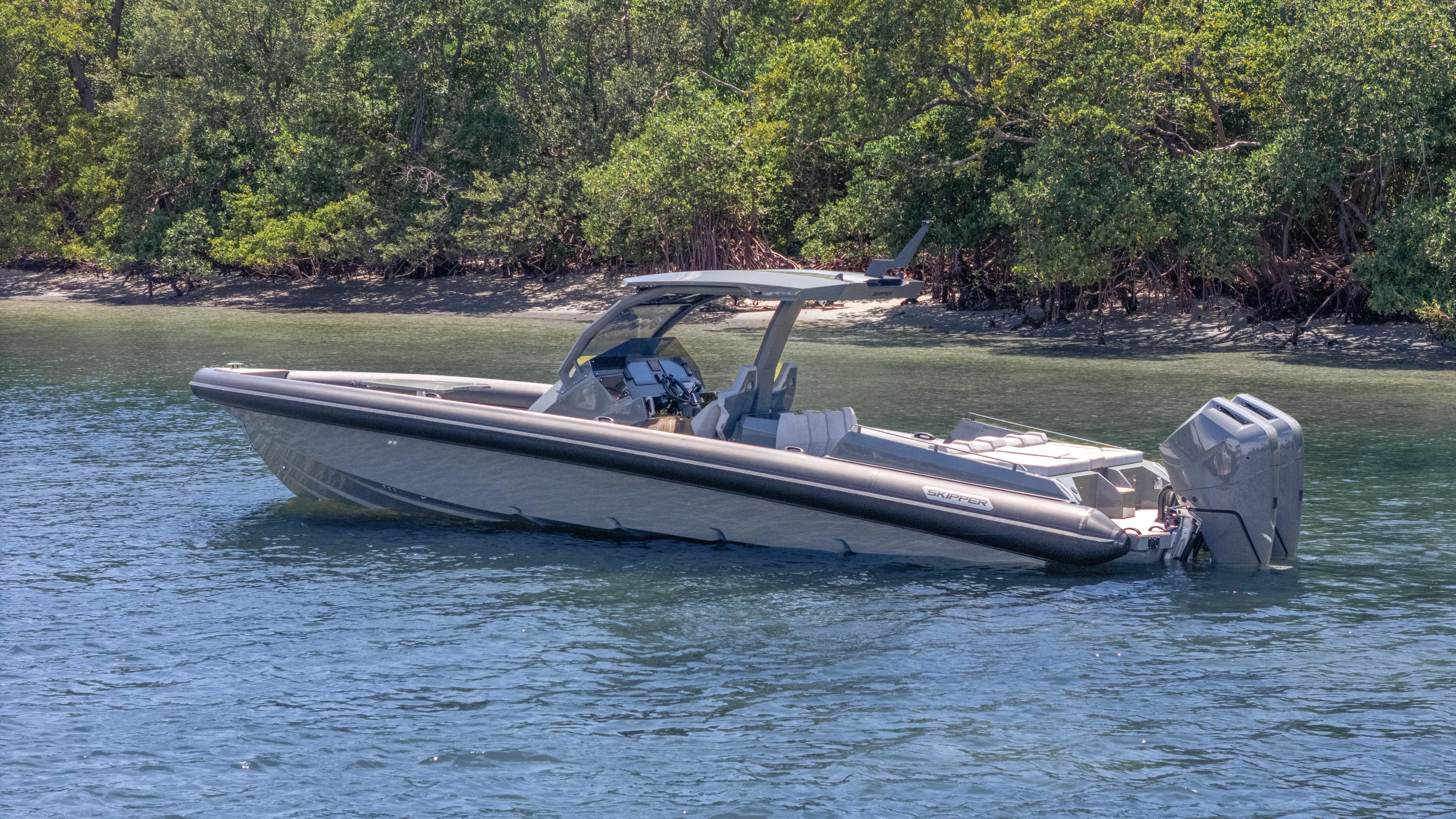 Skipper 38 Twin Mercury 400 Verado - Sunbed Ed. Yacht Photos Pics 2025 Skipper-BSK 38 boat on calm water near lush green shoreline.