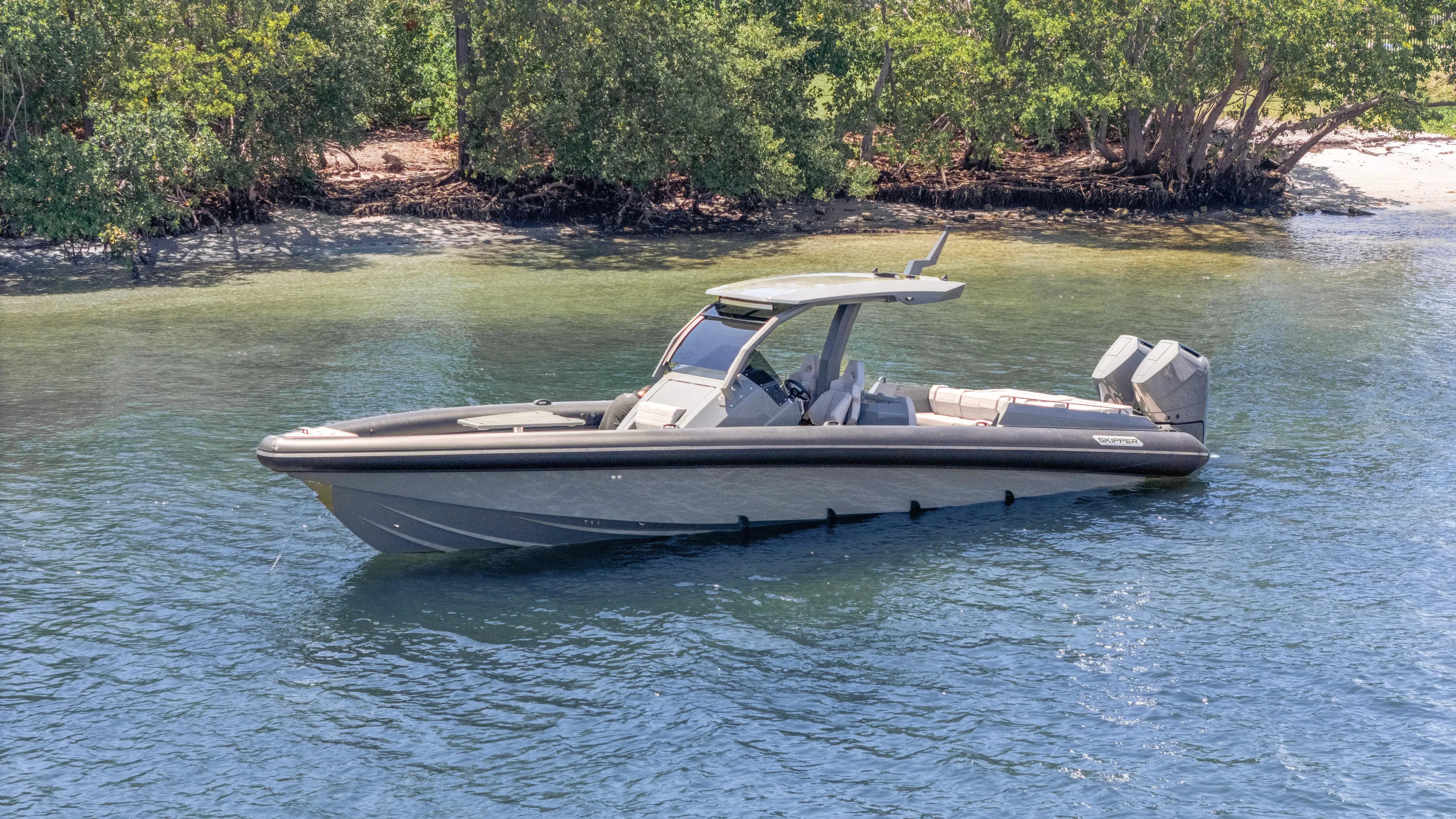 Skipper 38 Twin Mercury 400 Verado - Sunbed Ed. Yacht Photos Pics 2025 Skipper-BSK 38 boat on calm water near a lush shoreline.