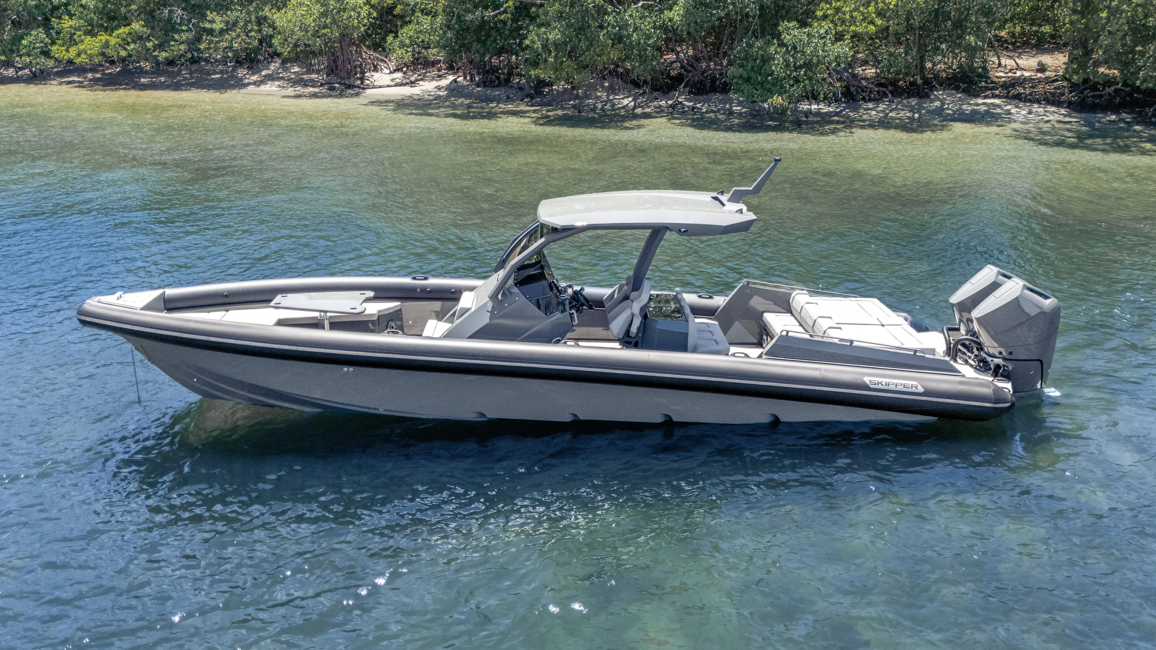 Skipper 38 Twin Mercury 400 Verado - Sunbed Ed. Yacht Photos Pics 2025 Skipper-BSK 38 boat on calm water near a lush shoreline.