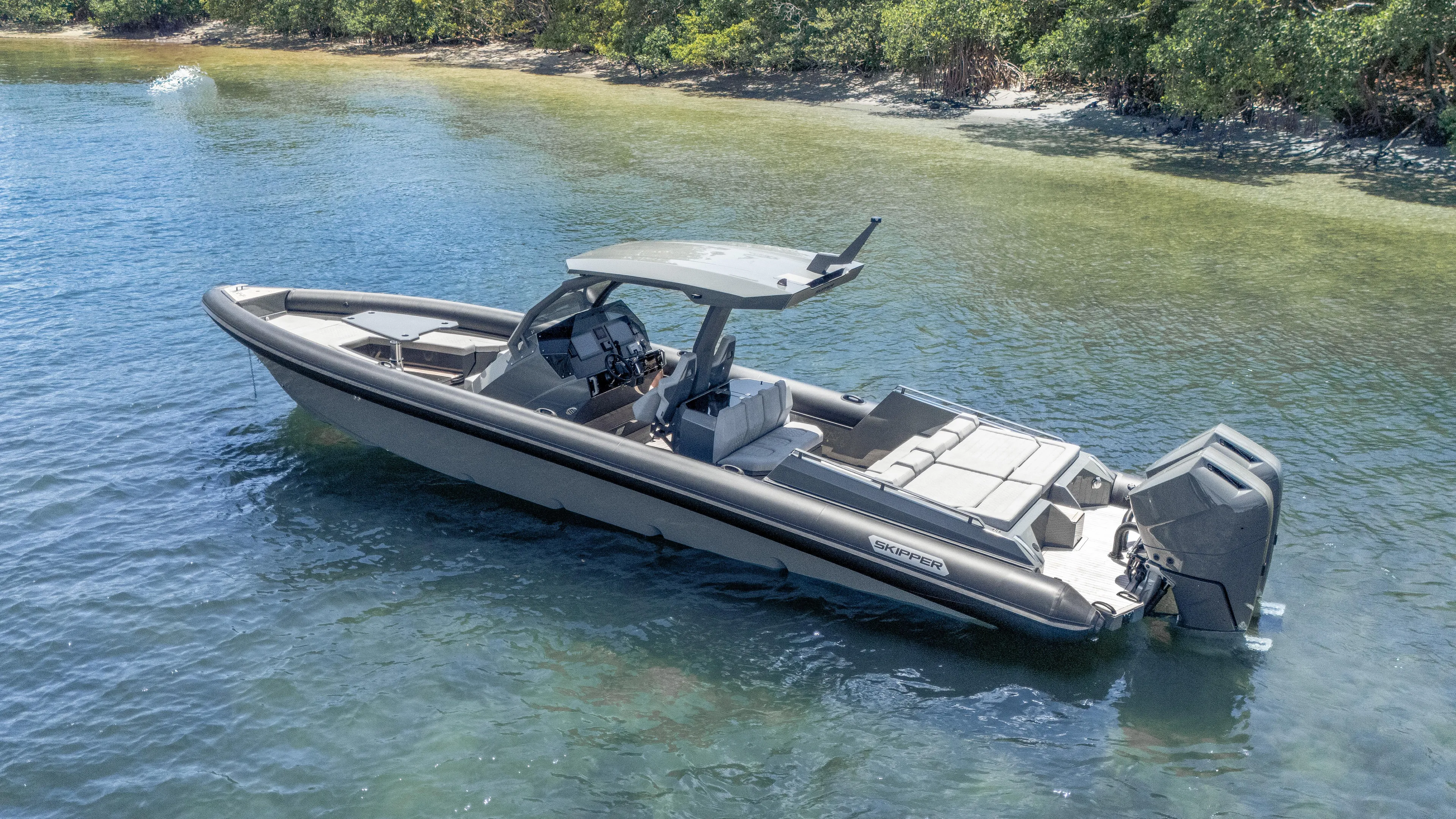 Skipper 38 Twin Mercury 400 Verado - Sunbed Ed. Yacht Photos Pics 2025 Skipper-BSK 38 boat on clear water near a lush shoreline.