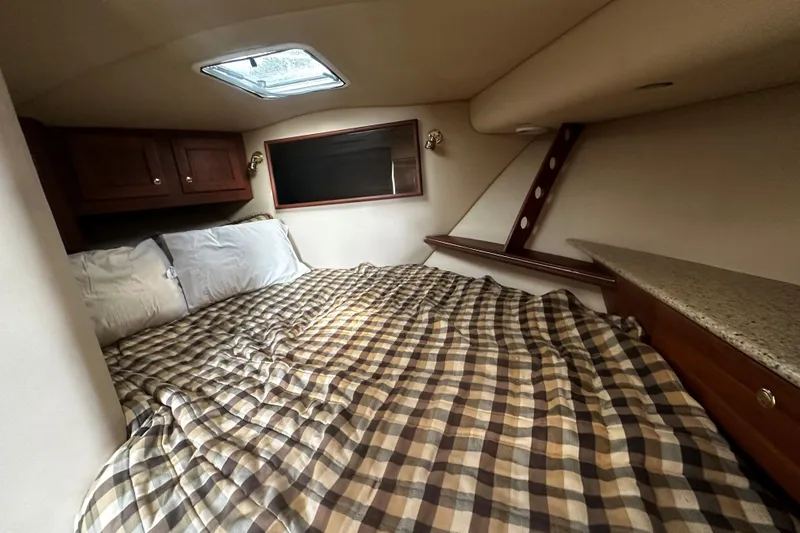 Miss Cissa Yacht Photos Pics Cozy cabin interior of 2003 Rampage 38 Express with plaid bedding and wooden cabinets.