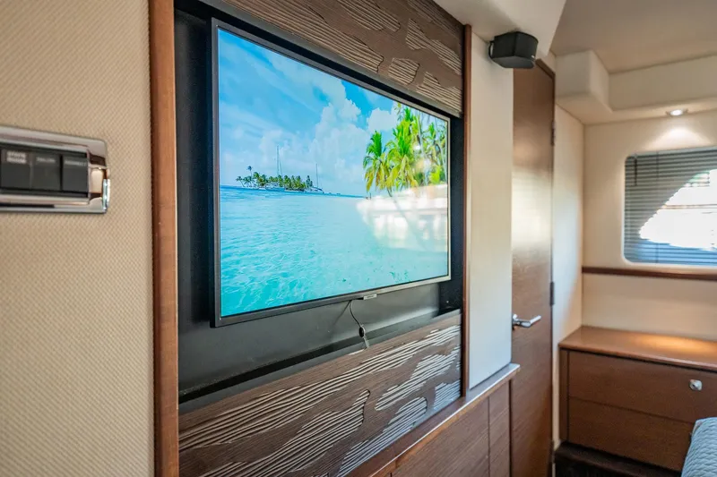 No Shoes Yacht Photos Pics Interior of 2013 Sea Ray 580 Sundancer yacht with wall-mounted TV displaying tropical beach scene.