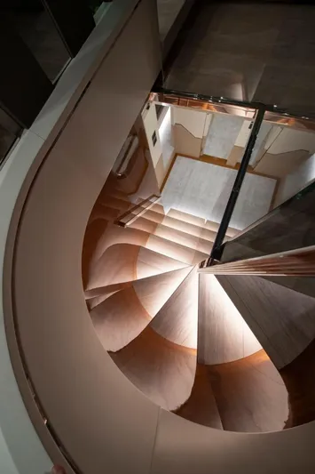 Yachting Conseil Yacht Photos Pics Spiral staircase inside 2025 Astondoa AX8 yacht, showcasing elegant wooden design.