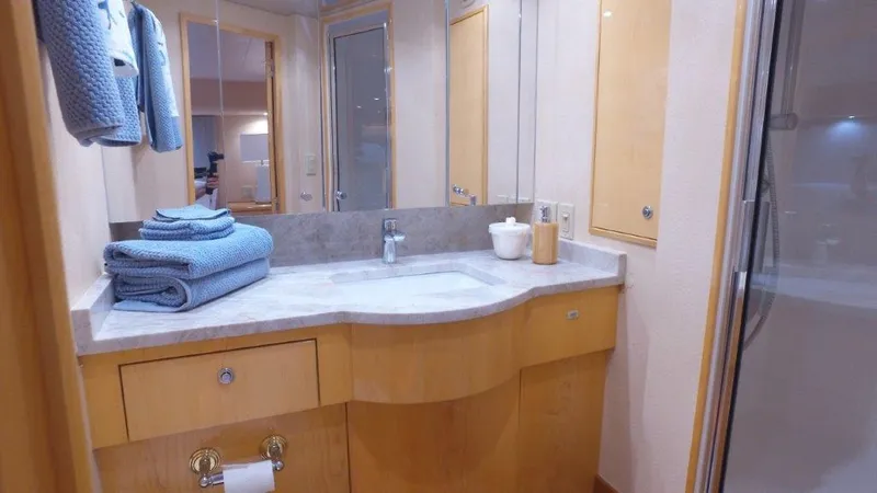 Jolley Roger Yacht Photos Pics Luxurious bathroom in 2006 Hatteras Enclosed Bridge yacht with modern fixtures and blue towels.