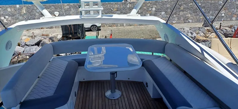  Yacht Photos Pics 2006 Sunseeker Manhattan 60 yacht with outdoor seating and table, docked by a stone wall.