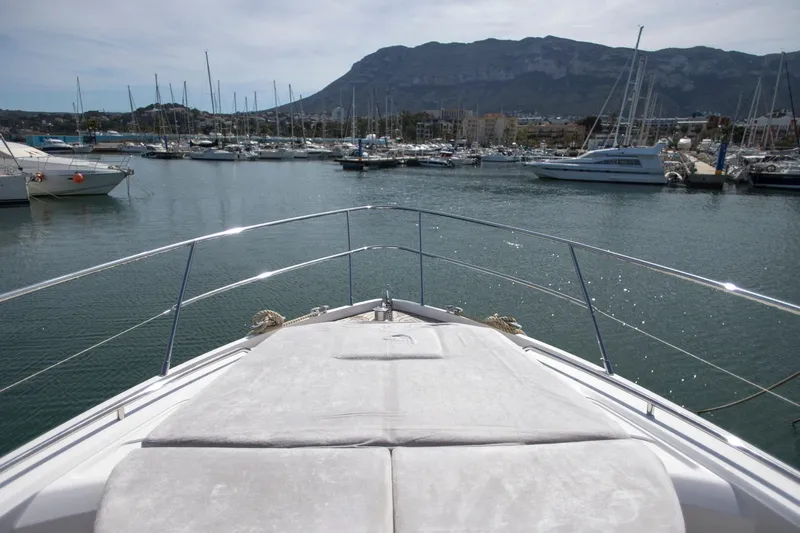  Yacht Photos Pics Bow view of 2022 Princess S66 yacht in a marina with mountain backdrop.