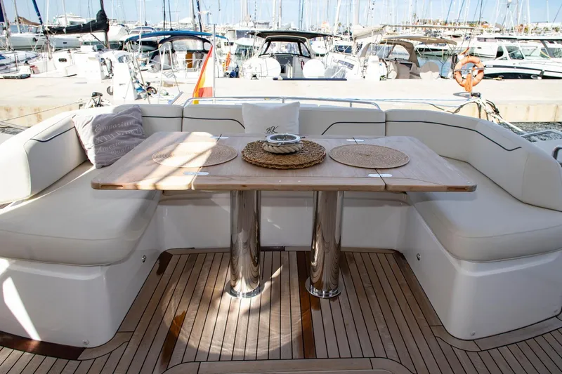  Yacht Photos Pics Luxurious 2022 Princess S66 yacht deck with elegant seating and wooden table in marina setting.