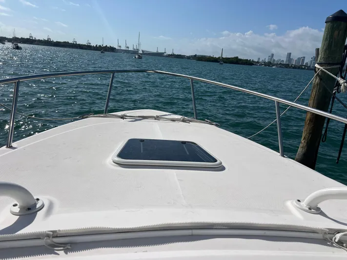  Yacht Photos Pics Bow view of 2014 Everglades 350LX boat on the water, city skyline in background.