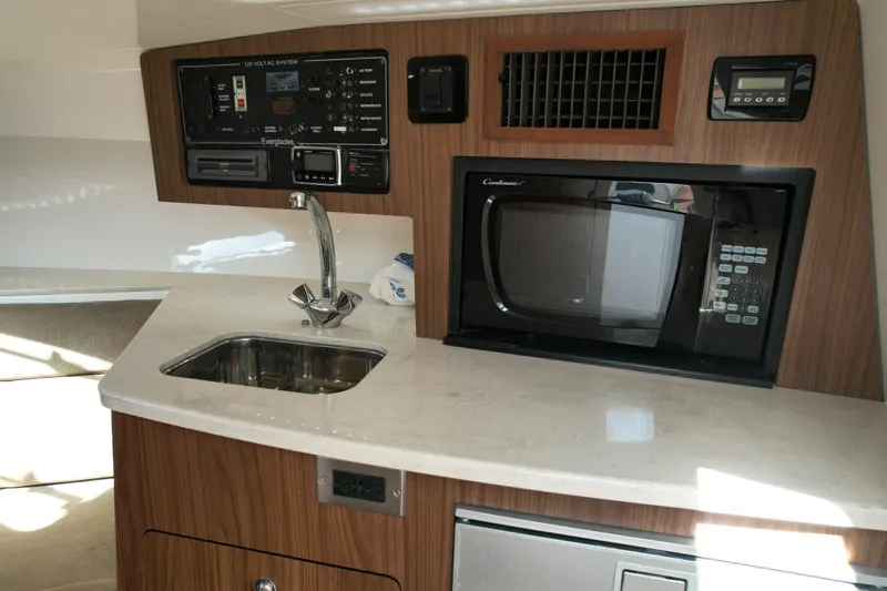  Yacht Photos Pics 2014 Everglades 350LX boat interior with kitchenette, featuring sink, microwave, and control panel.