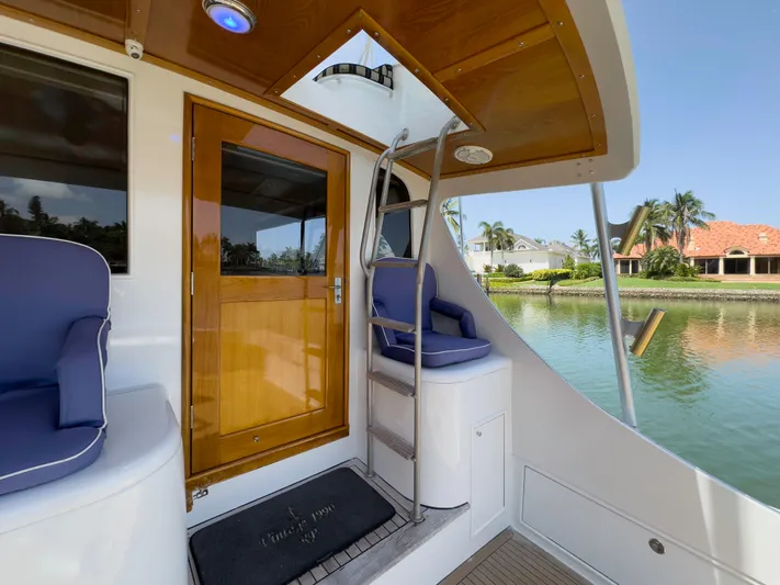 Vintage 1990 Yacht Photos Pics 1990 Buddy Davis 61 Convertible yacht with wooden door and seating area by the water.