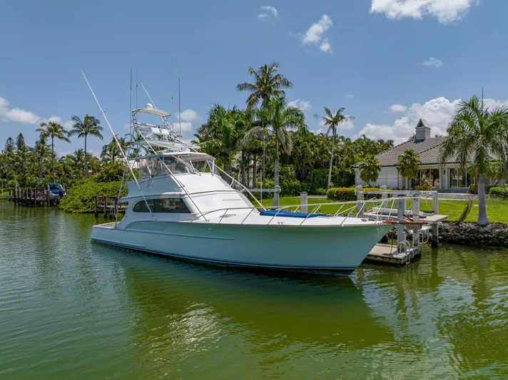 Vintage 1990 Yacht Photos Pics 1990 Buddy Davis 61 Convertible yacht docked near palm trees and waterfront property.