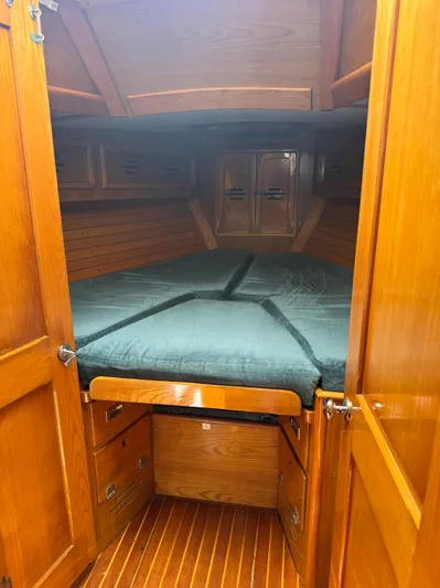 Mast Transit Yacht Photos Pics Cozy cabin interior of 1983 Hinckley Sou'wester 42 sailboat with wooden finish and green bedding.