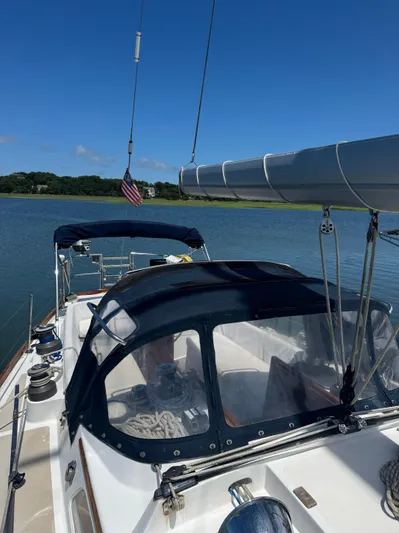 Mast Transit Yacht Photos Pics 1983 Hinckley Sou'wester 42 sailboat on calm water, featuring a blue canopy and American flag.