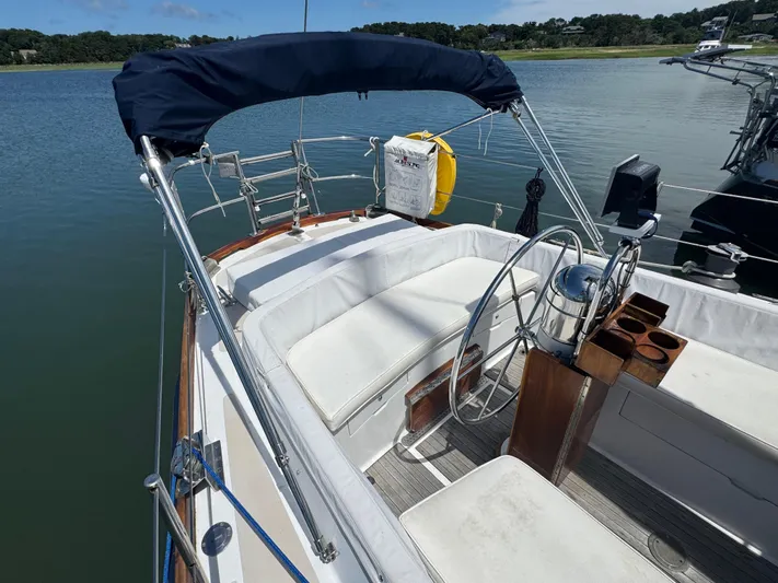 Mast Transit Yacht Photos Pics 1983 Hinckley Sou'wester 42 sailboat cockpit with steering wheel and seating, docked on calm water.