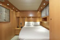 Luxurious cabin interior of 2009 Maiora 31 yacht with modern wood paneling and cozy bedding.