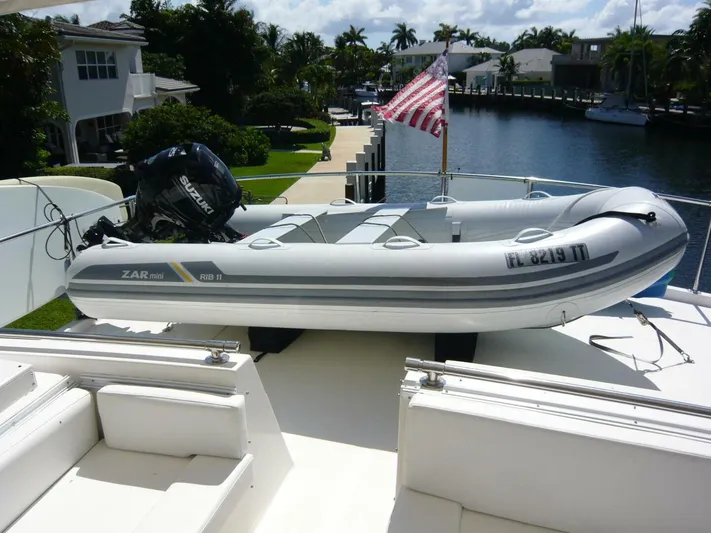 Vitamin Sea Yacht Photos Pics Inflatable boat on 1990 Viking Cockpit Motor Yacht with Suzuki outboard motor, docked by waterfront homes.