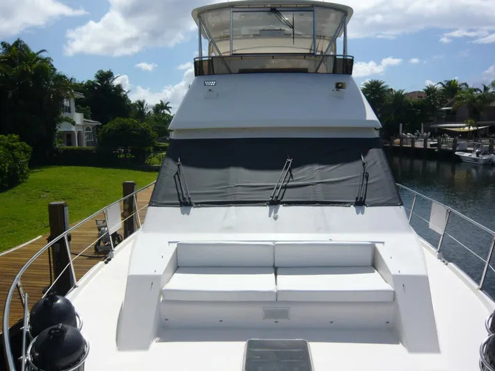 Vitamin Sea Yacht Photos Pics 1990 Viking Cockpit Motor Yacht with spacious deck seating, docked by lush greenery and waterfront homes.