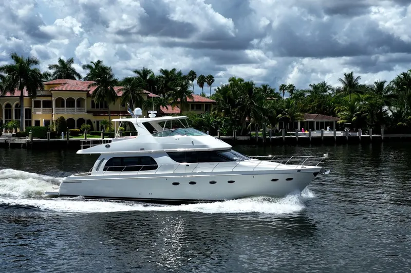Sound Traveler Yacht Photos Pics 2005 Carver 56 Voyager yacht cruising near waterfront homes under cloudy skies.