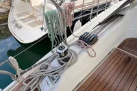 Hanse 345 sailboat deck, 2014 model, featuring ropes and winch on wooden surface.