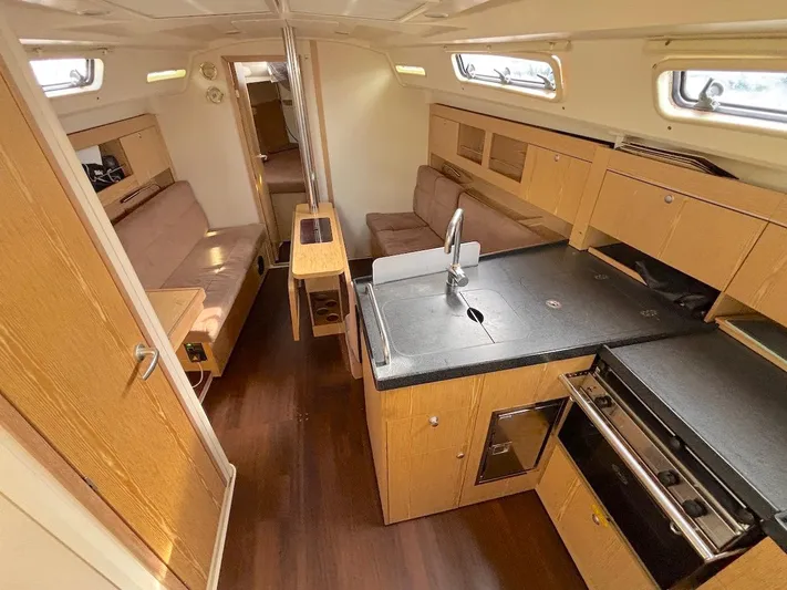 Sunshine Yacht Photos Pics 2014 Hanse 345 yacht interior with modern kitchen, wooden cabinetry, and cozy seating area.