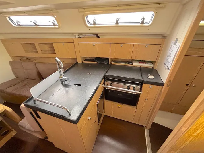 Sunshine Yacht Photos Pics Interior of 2014 Hanse 345 yacht featuring a compact kitchen with wooden cabinetry.