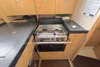 Compact kitchen in a 2014 Hanse 345 yacht with stove, oven, and wooden cabinetry.