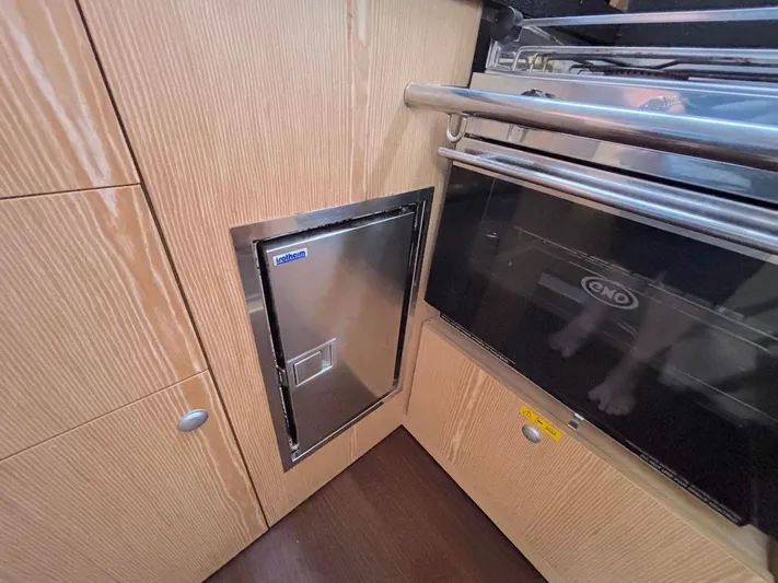 Sunshine Yacht Photos Pics Interior of 2014 Hanse 345 yacht kitchen with stainless steel appliances and wooden cabinetry.