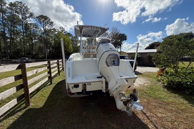 2017 Stuart 27 boat with outboard motor, parked on grass under a partly cloudy sky.