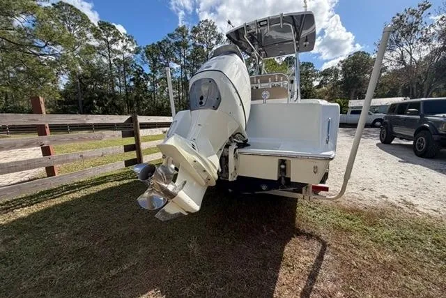  Yacht Photos Pics 2017 Stuart 27 boat with outboard motor, parked outdoors near trees and vehicles.