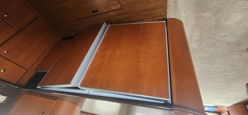  Yacht Photos Pics 2004 Silverton 48 Convertible interior with wooden cabinetry and foldable table.