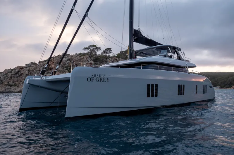 Shades Of Grey Yacht Photos Pics 2024 Sunreef 80 sailing catamaran "Shades of Grey" on serene waters at sunset.