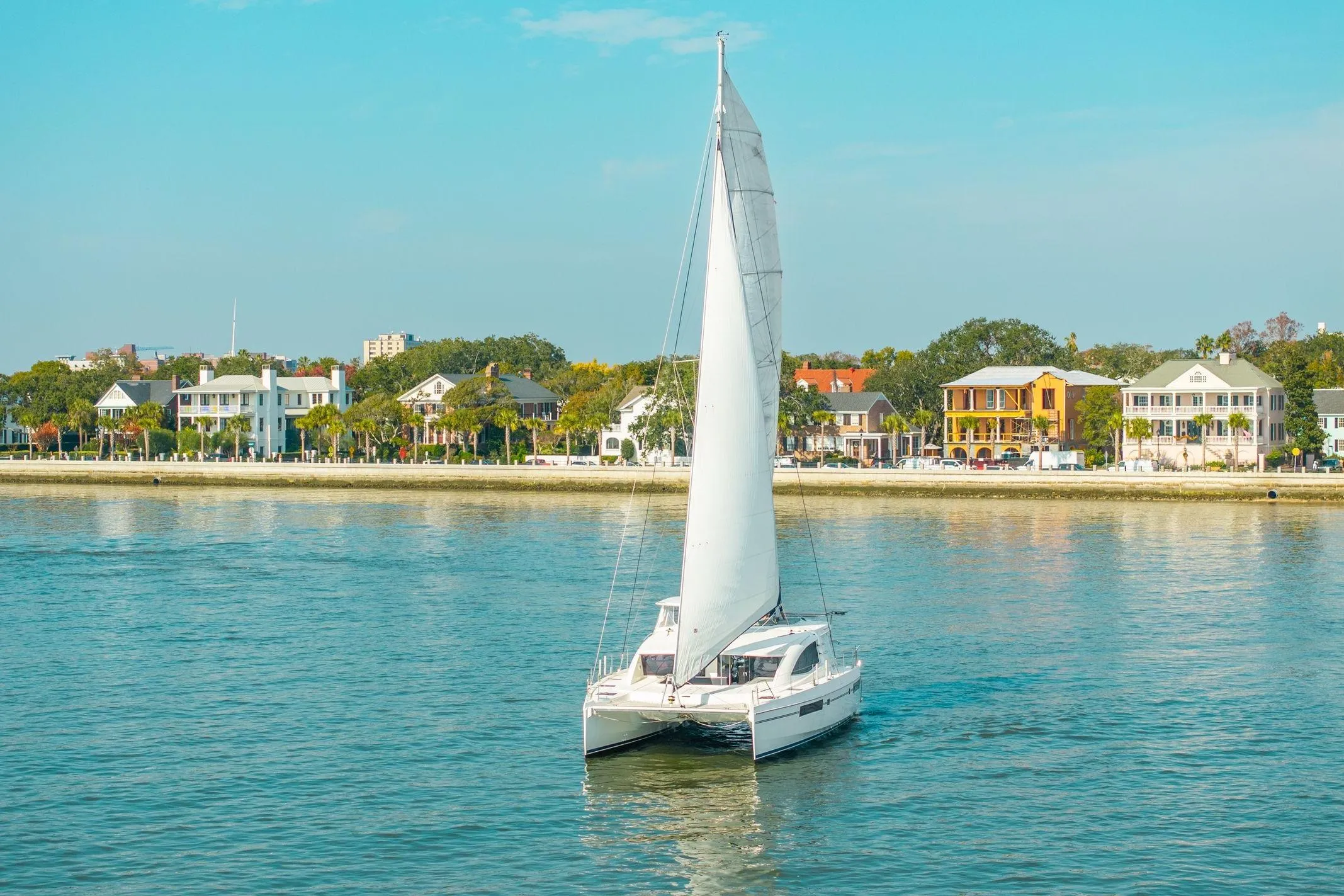 Sailing catamaran Leopard 48 on calm waters near colorful coastal homes, 2016 model.