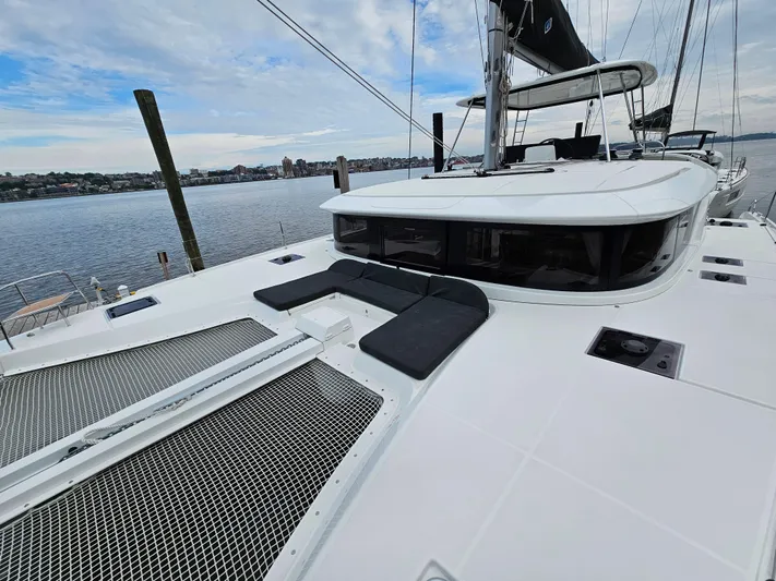  Yacht Photos Pics 2024 Lagoon 46 catamaran on calm water, showcasing spacious deck and sleek design.