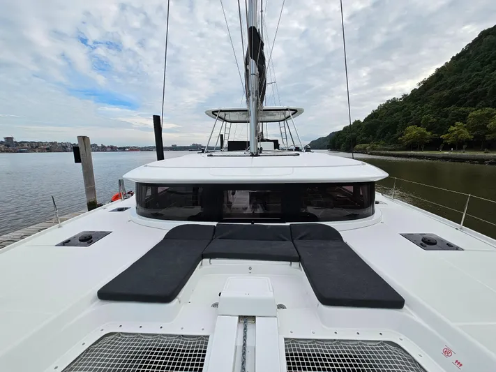  Yacht Photos Pics 2024 Lagoon 46 catamaran on calm river, featuring sleek design and spacious deck.
