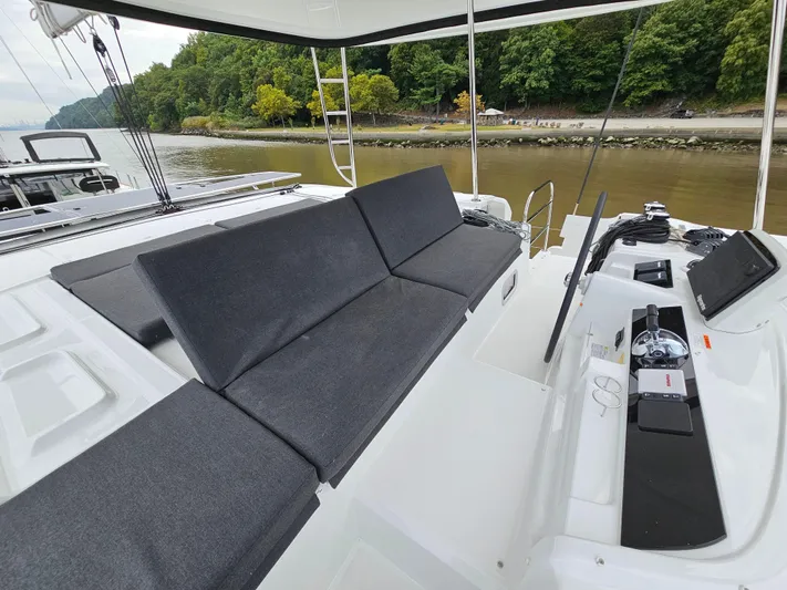  Yacht Photos Pics 2024 Lagoon 46 yacht deck with seating, overlooking a serene river and lush greenery.