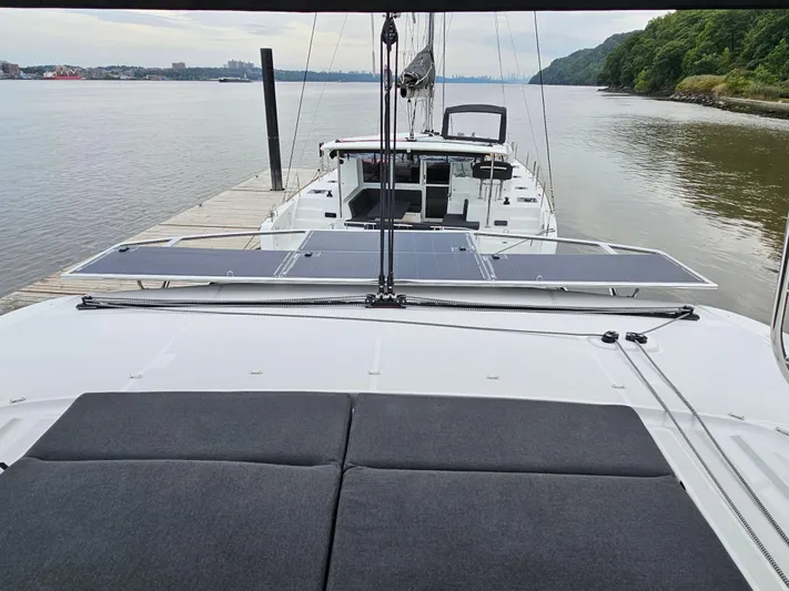  Yacht Photos Pics 2024 Lagoon 46 catamaran docked, featuring solar panels and spacious deck, on a serene river.