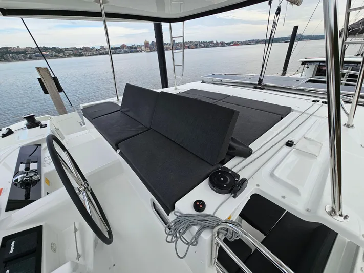  Yacht Photos Pics 2024 Lagoon 46 yacht cockpit with steering wheel and seating, overlooking calm waters.