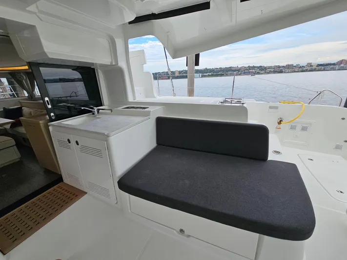  Yacht Photos Pics 2024 Lagoon 46 yacht interior with seating and kitchenette, overlooking serene water view.