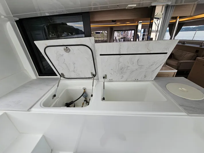  Yacht Photos Pics 2024 Lagoon 46 yacht interior with open storage compartments and sleek marble countertops.