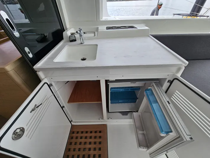  Yacht Photos Pics Modern kitchen area in 2024 Lagoon 46 yacht with sink, stove, and open storage.