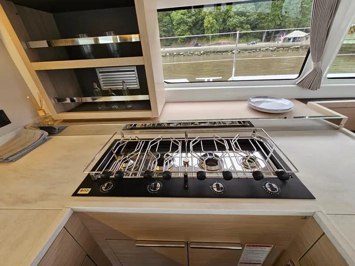  Yacht Photos Pics Modern kitchen in 2024 Lagoon 46 yacht with sleek stovetop and scenic window view.