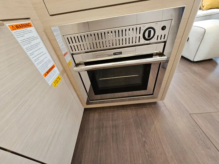  Yacht Photos Pics Modern oven in 2024 Lagoon 46 yacht kitchen, featuring sleek design and wood flooring.