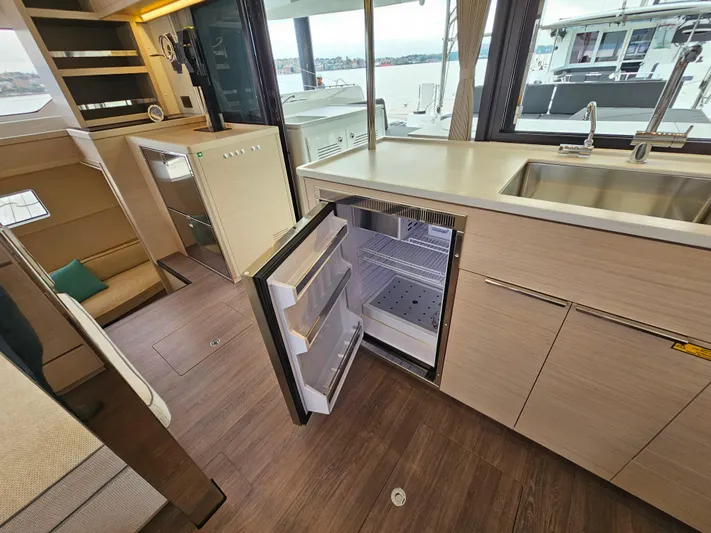  Yacht Photos Pics Modern kitchen interior of 2024 Lagoon 46 yacht with open fridge and sleek cabinetry.